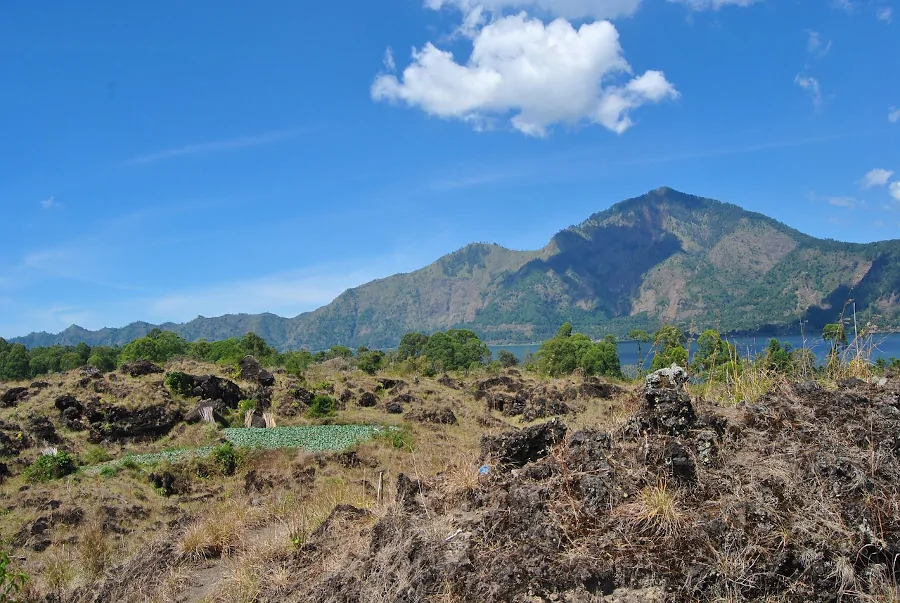 Paisaje volcánico del área de Batur con montañas, terreno de lava y el lago al fondo en Bali