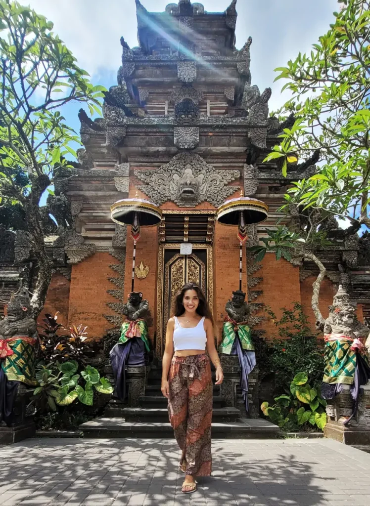 Entrada tradicional del Ubud Palace con una mujer frente al templo decorado en estilo balinés.