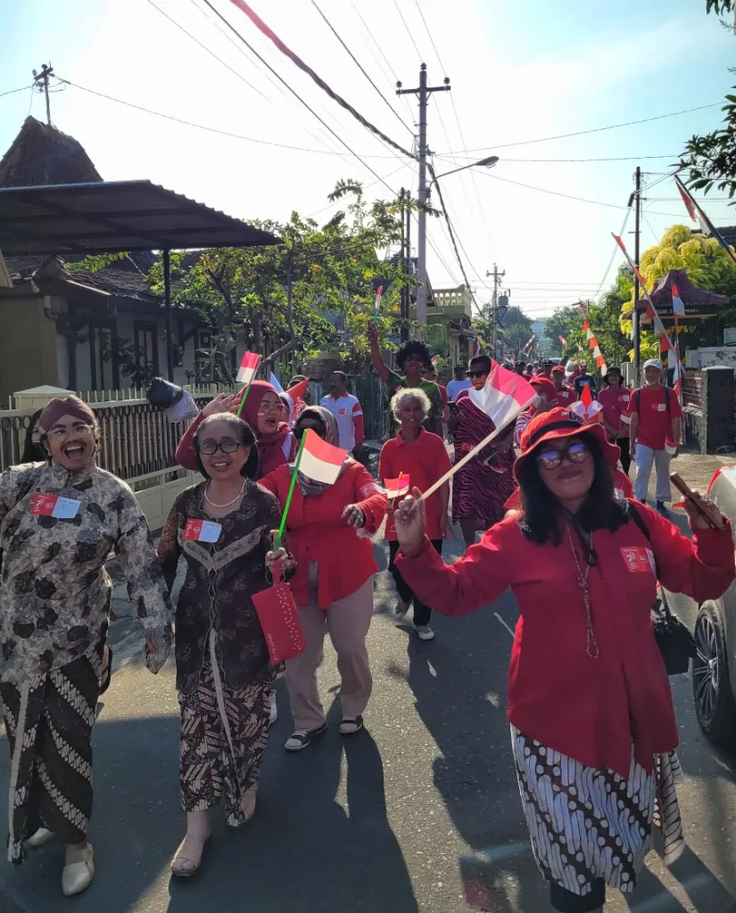 Celebración del aniversario de la independencia de Indonesia en las calles de Yogyakarta, con personas vestidas de rojo y banderas nacionales.