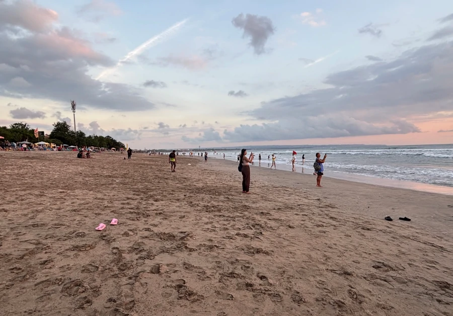 Legian Beach en Bali con arena amplia y personas caminando por la orilla del mar.