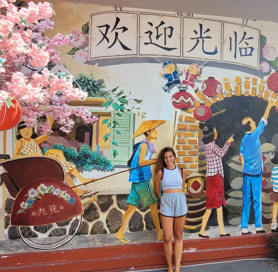 Mural de inspiración china en Pantjoran Chinatown con viajera posando frente a la ilustración.