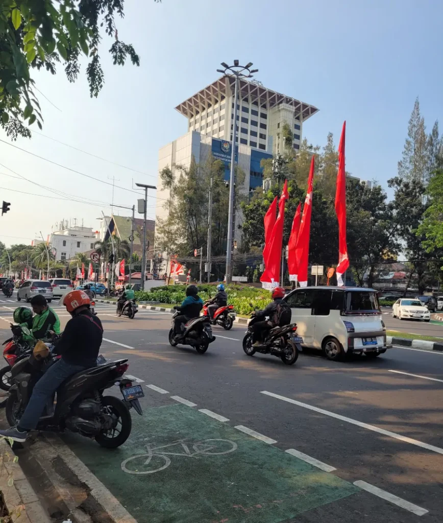 Calle de Yakarta con tráfico y espacio limitado para peatones, con carril bici y motos circulando