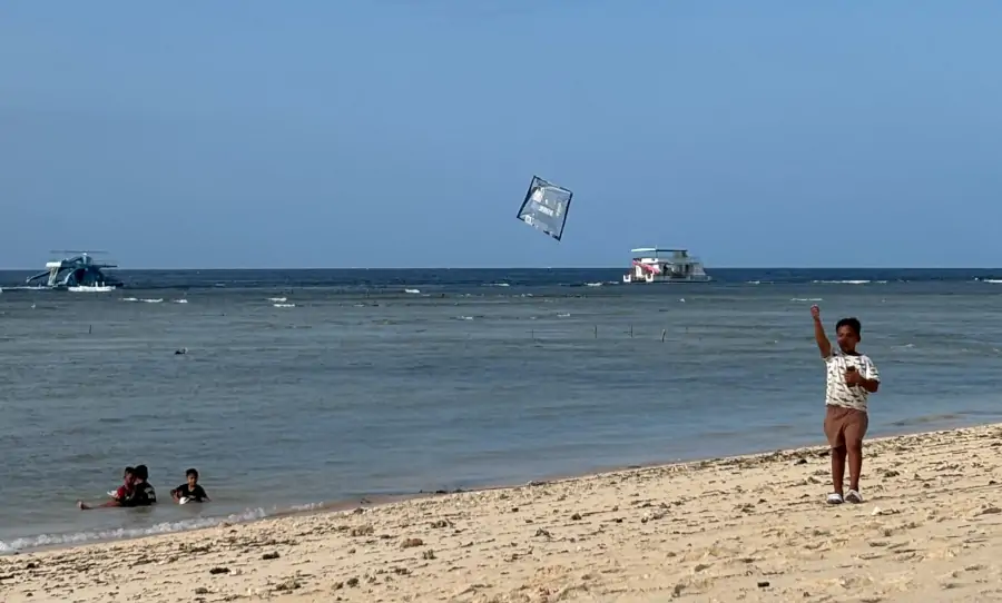 Niños jugando en la orilla de Mahagiri Beach, en Nusa Lembongan, mientras vuelan cometas junto al mar