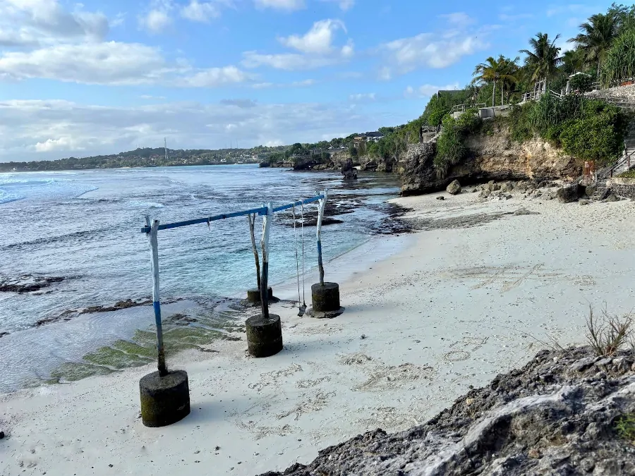 Secret Point Beach en Nusa Ceningan con arena blanca, rocas y un columpio junto al mar