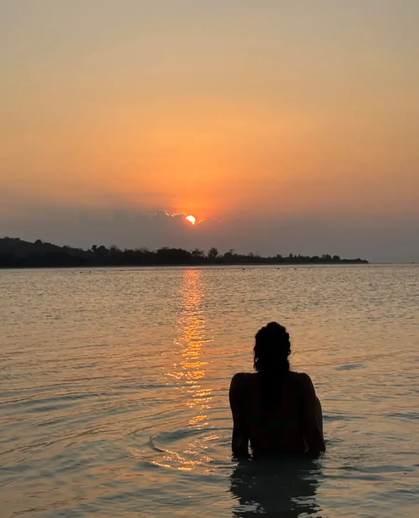 Atardecer en Gili Gede con una persona en el agua y el sol reflejándose en el mar