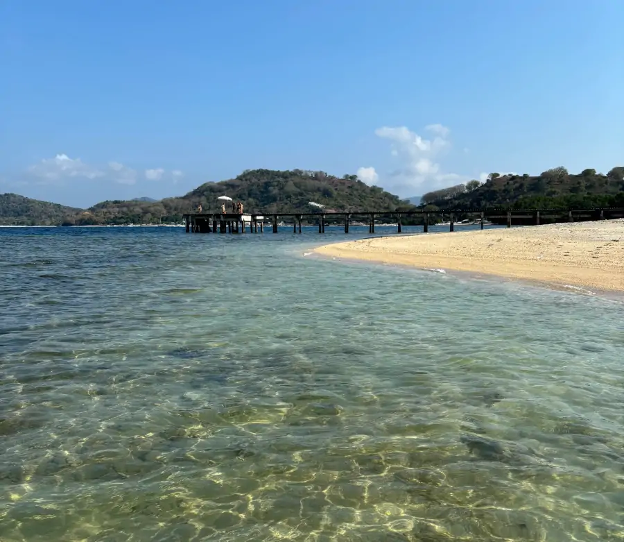 Playa de Gili Gede con agua cristalina y muelle de madera en Lombok
